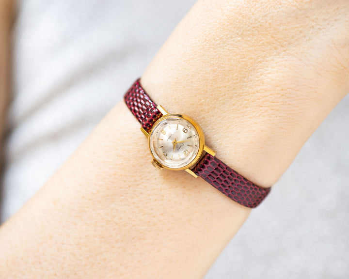 The tiny gold-plated watch on the woman’s wrist. The dial of the watch is with Arabic numerals, minimalist style, classic watch tiny little for every occasion. A piece of pre-owned vintage jewelry. You can make a better choice for the Planet.