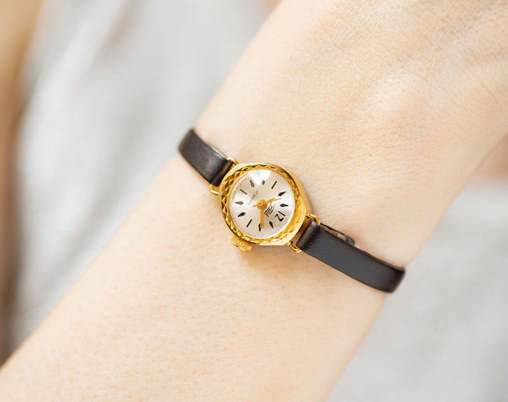 The tiny gold-plated watch on the woman’s wrist. The dial of the watch is with Arabic numerals, minimalist style, classic watch tiny little for every occasion. Never been used vintage jewelry. You can make a better choice for the Planet.