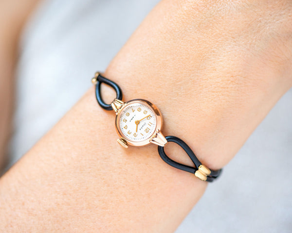 The tiny solid gold watch on the woman’s wrist. The dial of the watch is with Arabic numerals, minimalist style, classic watch tiny little for every occasion. A piece of pre-owned vintage jewelry. You can make a better choice for the Planet.